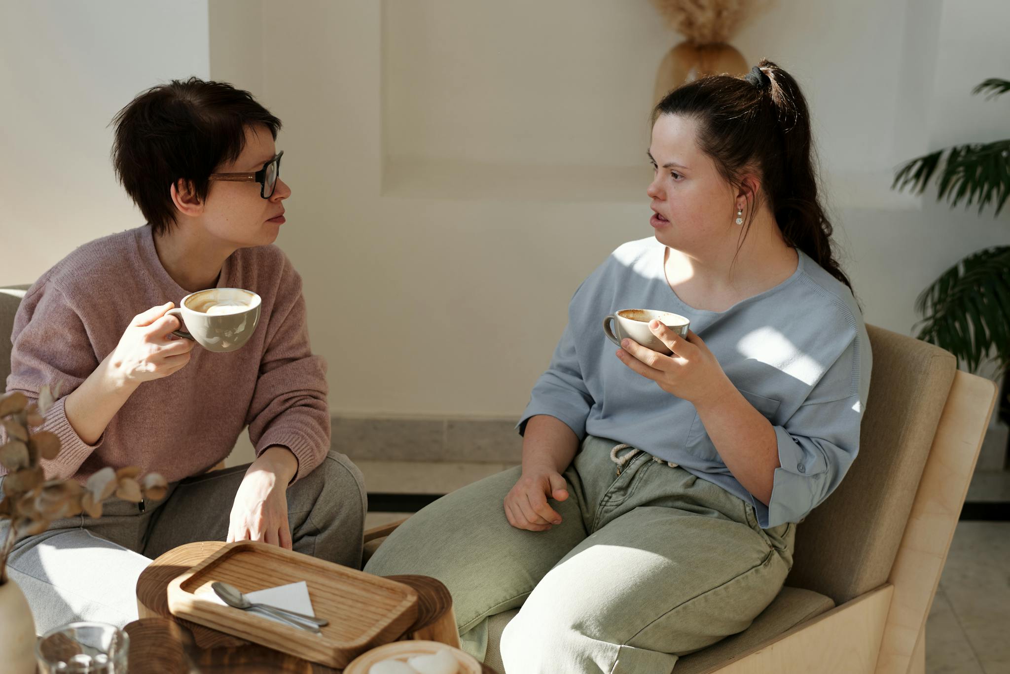Two women chatting over coffee in a cozy indoor setting, focused on togetherness and communication.